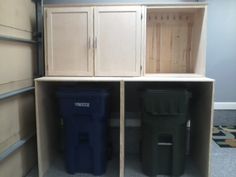 three trash cans are sitting in an empty storage unit with doors and cupboards on the sides