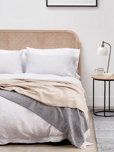 a bed with white linens and pillows in a small room next to a lamp