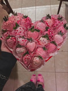 a heart shaped box filled with chocolate covered strawberries on top of a tiled floor