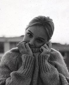 a black and white photo of a woman in a sweater talking on a cell phone