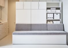 a couch sitting in front of a book shelf next to a white cabinet and sink