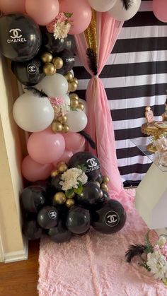 there is a bunch of balloons on the floor in front of a wall with chanel decorations