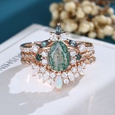 a green and white stone ring sitting on top of a table next to some flowers