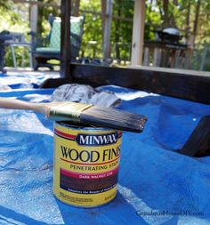 a paint can with a brush on top of it sitting on a blue tarp