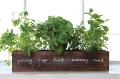 a wooden planter filled with herbs on top of a window sill