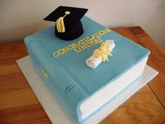 a graduation cake with a blue book and yellow ribbon on the top that says congratulations lindsy