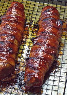 two sausages on a grill with sauce and ketchup are ready to be cooked