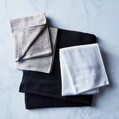 four towels folded on top of each other in black, white and grey linens