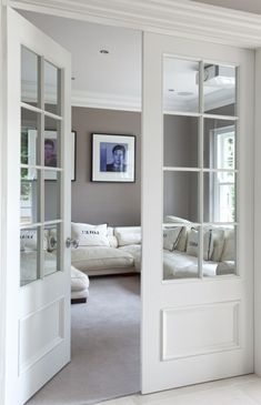 an open door leading to a living room with couches and pictures on the wall