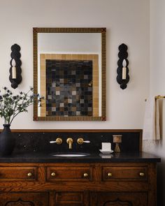 a bathroom vanity with two sinks and a large mirror above it, along with decorative wall hangings