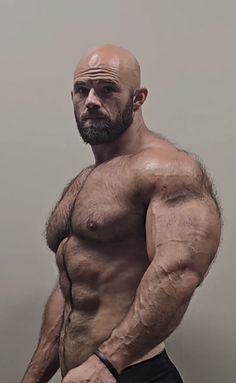 a bald man with no shirt standing in front of a wall