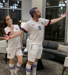 a man and woman in soccer uniforms standing next to each other with their arms outstretched