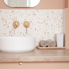 a white sink sitting under a bathroom mirror next to a wooden shelf with towels on it