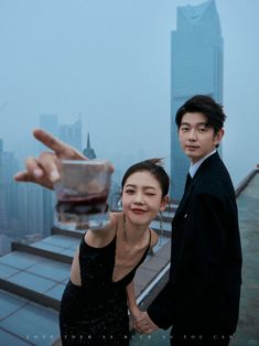 a man and woman standing next to each other on top of a building