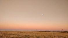 the sun is setting in the distance over an empty field with no grass on it