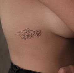 a woman's stomach with a tattoo on her left side, which has swirls in the shape of clouds