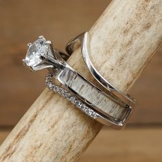 two wedding rings sitting on top of a piece of wood with diamonds in the middle