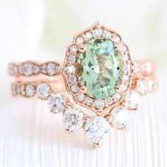 a ring with an oval green stone surrounded by smaller round diamonds on top of it