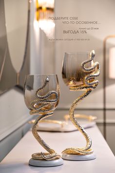 two wine glasses sitting on top of a counter next to each other with gold chains wrapped around them