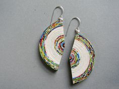 two pairs of earrings made out of paper on top of a gray surface with silver earwires