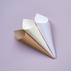 three paper cones on a purple surface one is folded and the other is rolled up