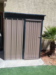 an outdoor storage shed in front of a building with a car parked next to it