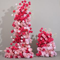 two large pink and red flowers sitting next to each other on top of a table