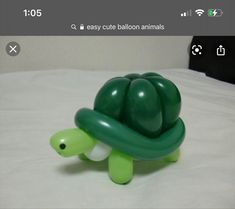 a green turtle toy sitting on top of a white bed