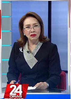 a woman sitting at a desk in front of a tv screen with the caption 24 news