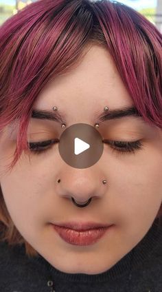 a woman with pink hair and piercings on her nose