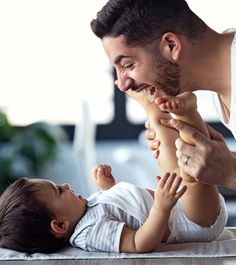 a man is playing with a baby on the floor while he holds it up to his chest