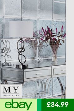 a mirrored table with vases and flowers on it in front of a mirror wall