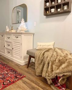 a living room with white furniture and rugs on the wooden floor next to a large mirror