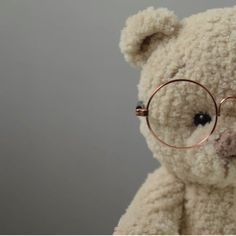 a teddy bear with glasses on it's face is shown in front of a gray background