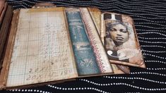 an open book with writing on it sitting on top of a black cloth covered table