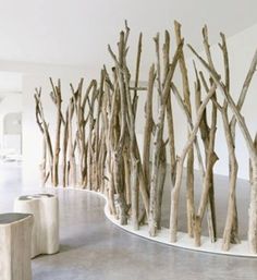 there is a sculpture made out of branches in the middle of a room with white walls