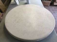 a large white round table sitting on top of a counter next to boxes and other items