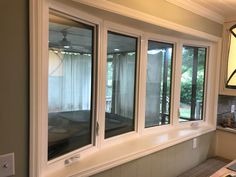 an empty kitchen with three windows and a lamp hanging from the ceiling over the counter