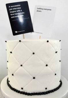 there is a white cake with black decorations on it and a card stuck to the top