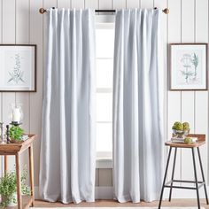 a white curtain hanging on the side of a window in front of a wooden table