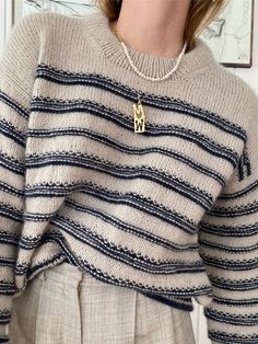 a woman wearing a sweater with a gold pendant