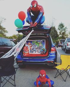 a spiderman is sitting on the back of a car with balloons attached to it