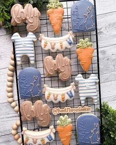 decorated cookies are displayed on a wire rack with greenery in the background, including carrots and succulents