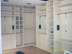 an empty walk in closet with lots of white shelves and drawers on the wall,