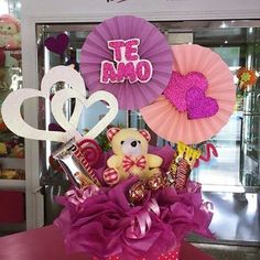 a teddy bear sitting in a basket with candy and decorations on the table next to it