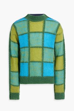 a green sweater with blue and yellow squares on the front, sitting on a white surface