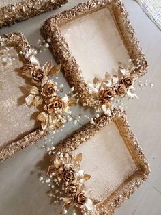 three gold frames with flowers and pearls on the edges are sitting next to each other