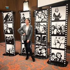 a woman standing in front of three black and white film strip wall panels with images of people on them