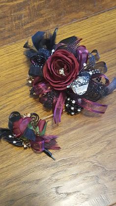 two hair pins with flowers on them sitting on a wooden table next to each other