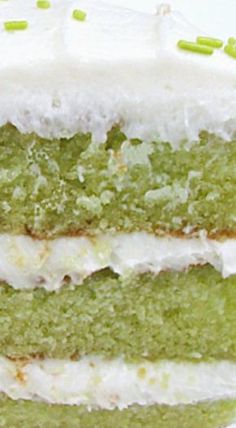 a green cake with white frosting and sprinkles sitting on a plate